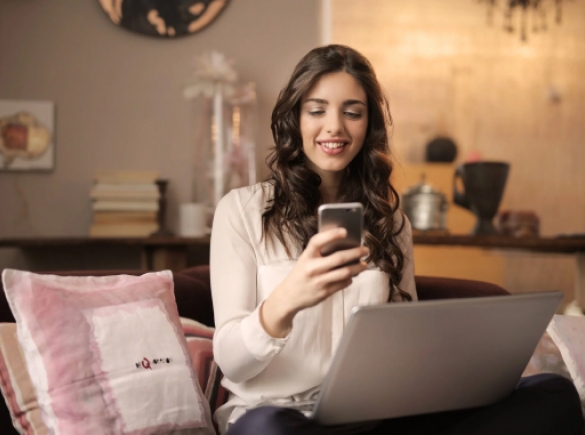 smiling woman using phone and computer