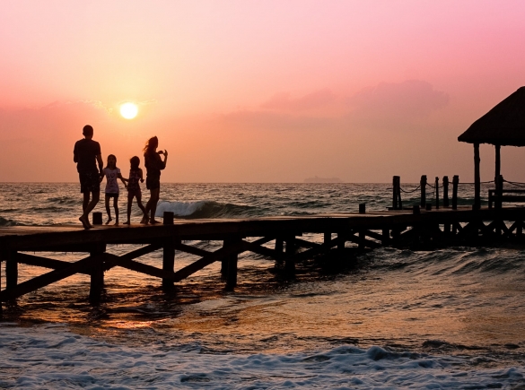 A family walking on a pier at sunset