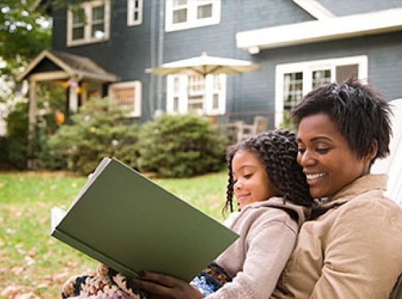 Mother and daughter reading in backyard