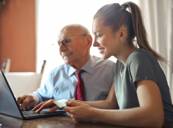 a young woman helps an elderly man with payment on a computer