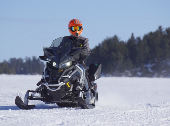 Man on snowmobile with forest in background