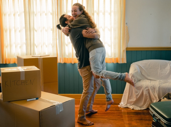 Photo of happy couple hugging, next to moving boxes