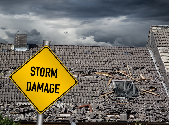 sign that says storm damage sits in front of damaged roof