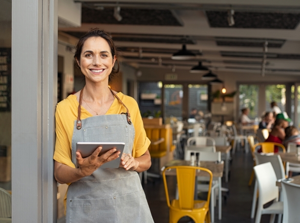 A successful business owner welcomes customers into her shop with a smile.