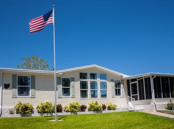 a mobile home with a flag and a blue sky behind it