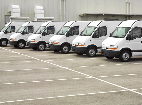 A fleet of white work vans parked in a lot.