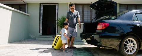 father and son loading car with suitcase