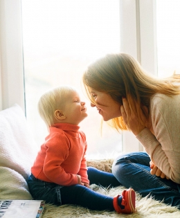 Mother and baby sitting in a window smiling at each other